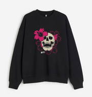 A black crewneck sweatshirt featuring a graphic print of a skull surrounded by vibrant pink flowers, displayed against a clean white background.