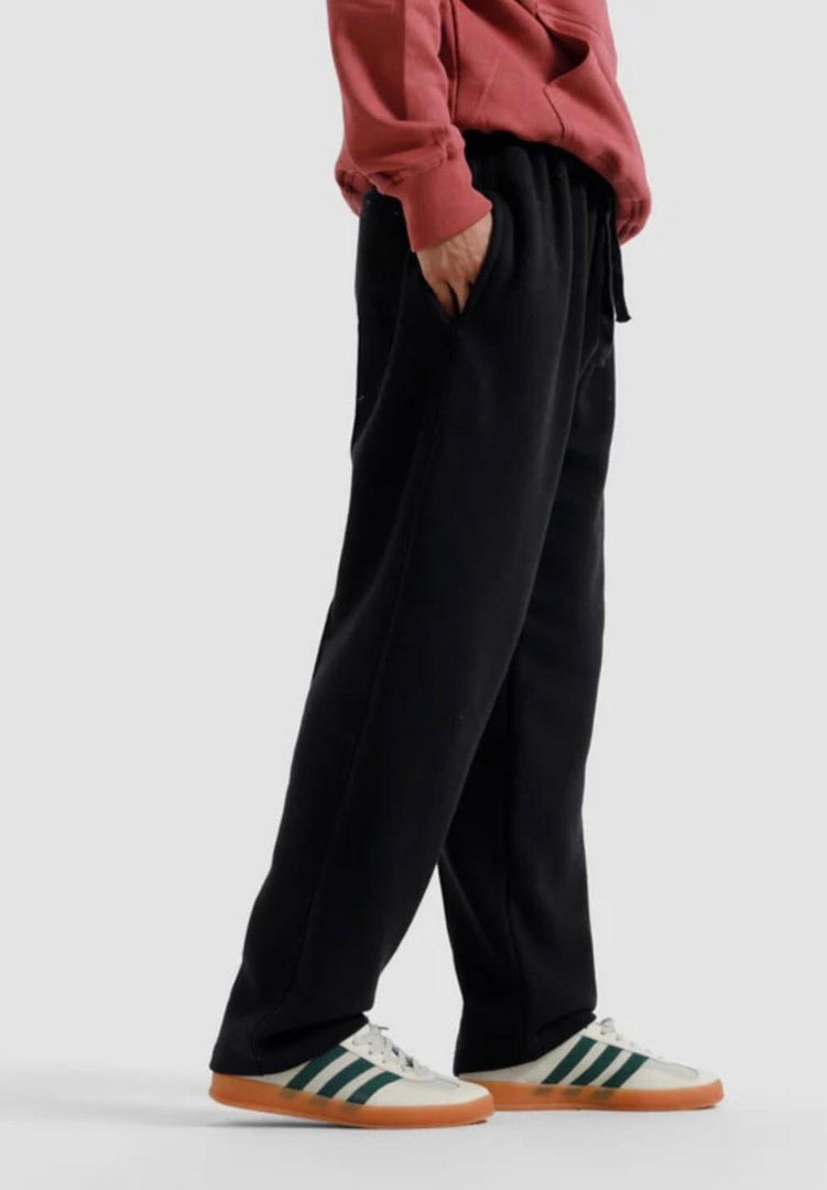 Person wearing black pants and a red hoodie with Adidas shoes on a light gray background