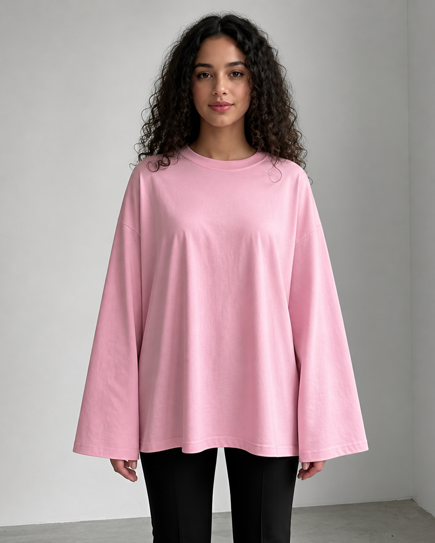 Woman wearing a pink oversized shirt against a plain background